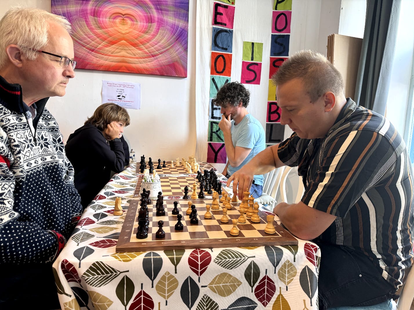 Four members playing on two boards at Bridge Street Cafe with local art on the walls